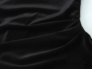 Dettaglio dell'abito in velluto nero con trama arricciata e lucentezza del tessuto