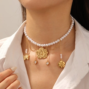Layered pearl necklace with gold flower and butterfly pendants on model neck