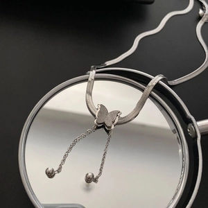 Frosted butterfly tassel necklace in silver finish on a round mirror reflective surface