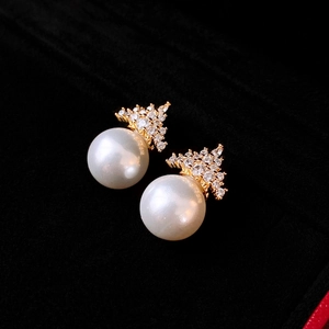 Macro shot of crown pearl earrings with sparkling zircon inlay on black velvet