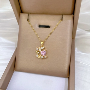 Close-up of pink heart zircon necklace with leaf accents in a gold jewelry box