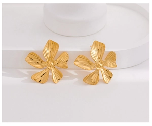 Detailed view of golden metal flower earrings with 3D brushed texture and petal design