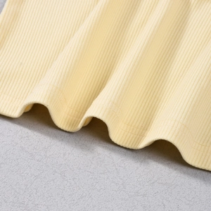 Detailed close-up of light yellow ribbed knit fabric texture and hem stitching quality