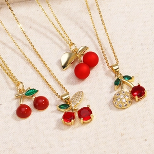 Macro detail of red cherry pendants with green zircon leaves on a soft beige fabric