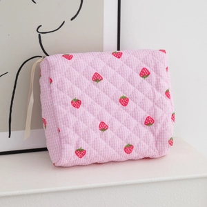 Detailed texture of pink checkered quilted cosmetic bag with cute strawberry print