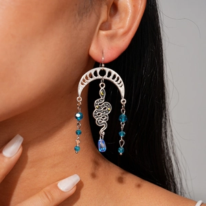 Detail of silver moon and snake earrings with blue crystal beads on a female model
