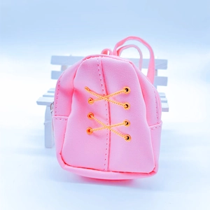 Close-up of pink mini backpack coin purse with golden lacing on a small white bench