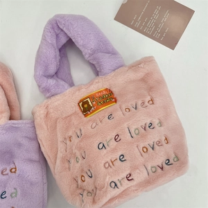 Détail du sac en peluche avec broderie colorée 'You are loved' et texture douce