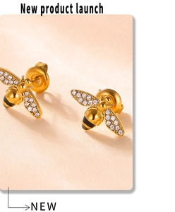 Detail of gold bee earrings with white crystals and black stripes on a beige background