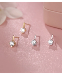 Close-up of S999 silver stud earrings with round cubic zirconia in gold and silver finish