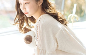 Close-up of elegant cream long-sleeve cotton top with lace details and hollow embroidery