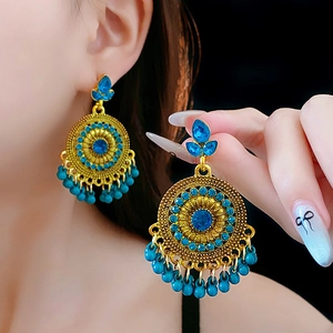 Macro detail of vintage gold floral earrings with blue gems and beaded tassels