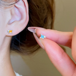 Gros plan de boucles d'oreilles étoile en émail bleu et orange avec cristaux brillants