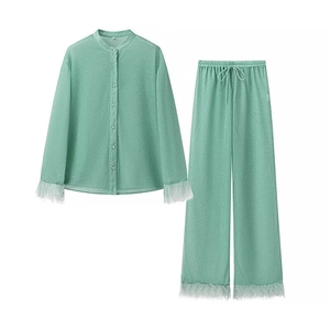 Vue détaillée de l'ensemble chemise et pantalon vert clair avec plumes blanches aux poignets