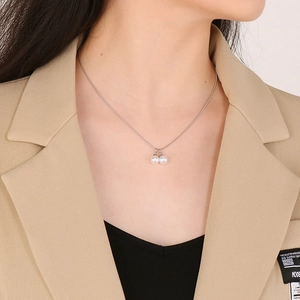Primo piano di una collana in acciaio al titanio argento con due pendenti in perle su modella