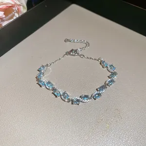 Detailed close-up of aquamarine zircon bracelet with silver bow and adjustable clasp