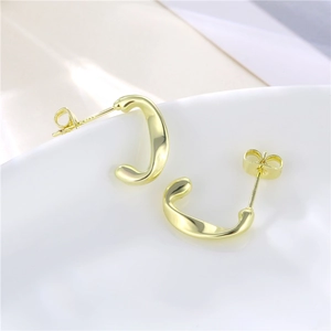 Minimalist 18K gold C-shape twisted earrings with polished finish on ceramic edge