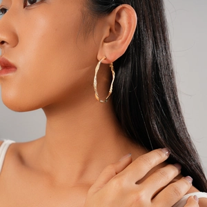 Gros plan d'un mannequin portant une boucle d'oreille créole torsadée dorée vintage