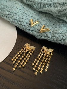 Detailed view of gold V-shaped stud earrings with elegant chain tassels and polished finish