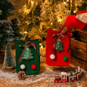 Detail of red and green felt Christmas gift bags with 3D tree charms and festive ribbons