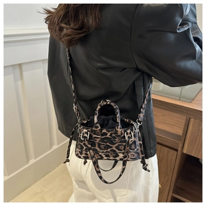 Close-up of leopard print crossbody bag with dual handles and adjustable strap detail