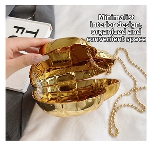 Detail of a heart-shaped gold evening clutch bag with a metallic bead chain