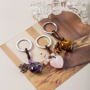 Three heart-shaped natural stone keychains in amethyst, rose quartz, and tiger eye stone