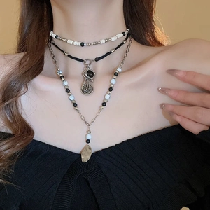 Detail of bohemian layered necklace with black beads and metallic geometric charms