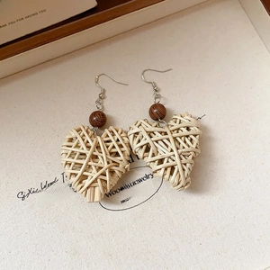Detail of bohemian heart-shaped woven earrings with brown wooden beads and silver hooks