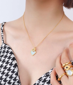 Détail du collier étoile avec nacre et bagues dorées superposées portés par un mannequin