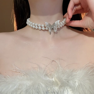 Close-up of double-layer pearl necklace featuring a silver butterfly pendant on woman