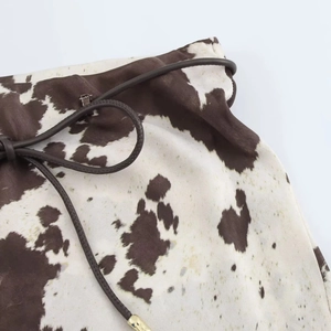 Gros plan sur le tissu à imprimé vache marron avec cordon en cuir et embouts dorés