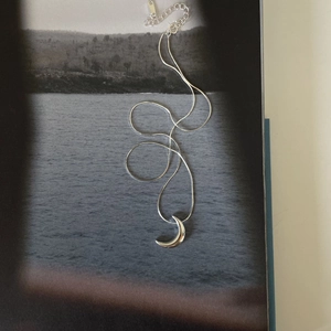 Artistic detail of silver moon pendant necklace on a minimalist photography background
