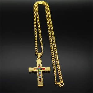 Detail of gold Cuban chain and cross pendant with multi-color gemstones on black background