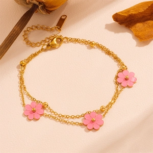 Detailed macro view of a gold double-layer daisy bracelet with three pink flower pendants