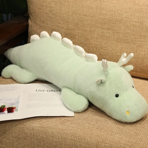 Close-up of soft green plush dinosaur toy with fluffy texture on a beige sofa