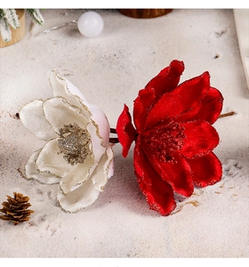 Close-up of velvet Christmas flowers in red and cream with glitter on artificial snow