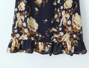 Close-up of floral print ruffle hem on a navy blue slim-fit chiffon camisole dress