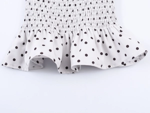 Detailed view of the elastic smocked waist and ruffled hem with black polka dot pattern