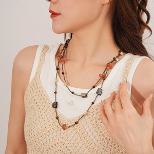 Gros plan d'un collier bohème double couche avec perles de coquillage rouges et bois