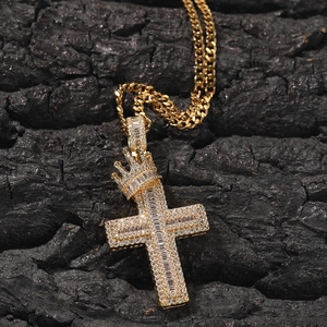 Golden crown cross pendant necklace with zircon stones on black rock surface