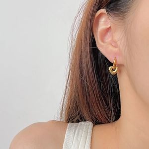 Gros plan d'élégantes créoles cœur dorées portées par un mannequin pour un look chic