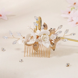 Macro detail of bridal hair comb featuring white ceramic flowers and crystal leaves