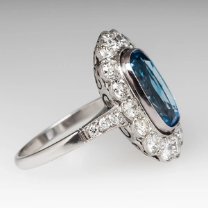 Macro side view of luxury blue oval gemstone ring with diamond halo and intricate carving