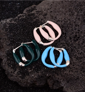 Detail of colorful enamel S925 silver earrings on black volcanic rock texture