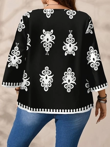Elegante zwarte tuniek met witte bloemenprint en halflange mouwen gezien vanaf de rug