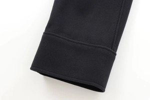 Détail du poignet d'un manteau noir montrant les coutures et la texture épaisse en laine