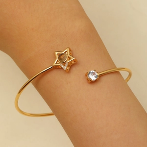 Détail d'un bracelet ouvert doré avec étoile et zircon montrant les cristaux sertis