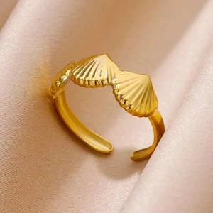 Detail shot of golden seashell open ring on pink silk background with metallic texture