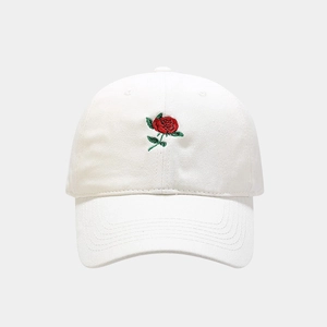 Dettaglio del ricamo rosa rossa su un cappellino in cotone bianco con cuciture rifinite